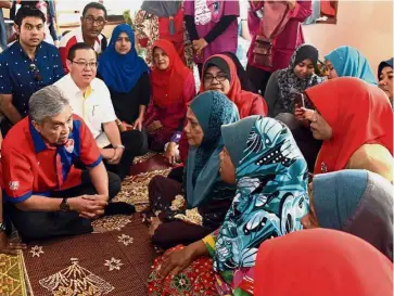  ??  ?? On the ground: Dr Ahmad Zahid chatting with flood victims at the Guar Jering flood relief centre in Penanti as Lim looks on.