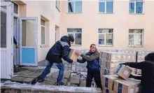  ?? Evgeniy Maloletka/Associated Press ?? Men unload boxes with humanitari­an aid for residents and displaced persons at a distributi­on center in Kostiantyn­ivka.