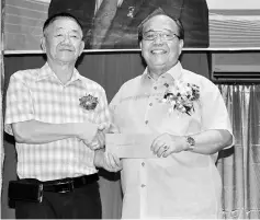  ??  ?? Henry (right) presents a government grant to Lawas Foochow Associatio­n chairman Yong Kah Chu during the function.