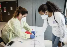  ?? Miami Dade College ?? MDC staff verify the temperatur­e of their students and teachers at the Hialeah Campus checkpoint on June 23,