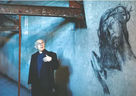  ?? YARA NARDI / REUTERS ?? Father Ezio Marcelli looks at a graffiti he discovered in the attic of the San Gioacchino church, where 35 people hid over nine months during the Nazi-fascist occupation of Rome between 1943-1944 and left their testimony of isolation and suffering through graffiti on the walls.