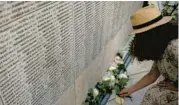  ?? CHRISTOPHE ENA/AP ?? A woman lays a flower on the Wall of Names during a ceremony Saturday at the memorial garden of the children of the Vel d’Hiv Roundup in Paris.