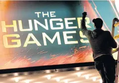  ??  ?? A worker swaps out the billboard marking the opening of The Hunger Games at the Ziegfeld Theatre in New York.