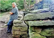  ?? [PHOTO BY MIKE SIMONS, TULSA WORLD] ?? Russ Hays, an employee and alumnus of the Oaks Indian Mission, leans on the original spring house foundation on the mission’s property in Oaks. Plans for a nearby chicken house were canceled when locals objected.