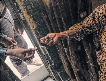  ?? /AFP ?? Against the rules: A man buys a cigarette from a woman at an undisclose­d location in April. This ordinary action has been criminalis­ed because the sale of alcohol and cigarettes has been banned during the national lockdown in SA.