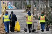  ?? (AP/Keith Srakocic) ?? Volunteers from the Pittsburgh Downtown Partnershi­p carry cleaning gear Sunday in downtown Pittsburgh.