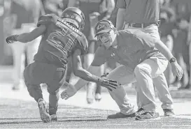  ?? Yi-Chin Lee / Houston Chronicle ?? Langham Creek’s Chris Mehn gets a low high-five from one of his coaches after scoring a touchdown in the first quarter of Saturday’s playoff game.