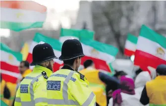  ??  ?? Police officers guard Anglo-Iranian communitie­s, supporters of Iran’s democratic opposition, as they hold a rally near 10 Downing Street in London on Thursday in solidarity with anti-regime protests in Iran.