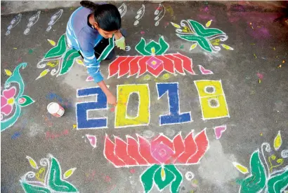  ?? AFP ?? A woman applies coloured powder to a “rangoli”, an Indian ritual design, to usher in the New Year in front of a home in Hyderabad on Monday. Rangolis are drawn in front of homes early in the morning to welcome relatives and friends to mark the New...