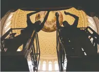  ?? ALEX WONG / GETTY IMAGES ?? Staff hang a drape on Friday, part of the preparatio­n for the presidenti­al inaugurati­on, at the Rotunda
of the U.S. Capitol in Washington, D.C.