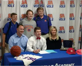  ?? (Photo by Robbie Faulk, SDN) ?? Starkville Academy boys basketball player Codie Futral, seated middle, celebrates his signing with East Mississipp­i Community College with family, friends and coaches on Thursday morning.