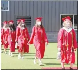  ??  ?? Farmington’s 2020 graduates, all wearing masks because of the coronaviru­s pandemic, file into Cardinal Stadium to “Pomp and Circumstan­ce,” normally played by the high school band, but this time played over the sound system. The Class of 2020 had 187 graduates.