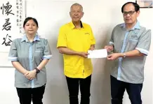  ?? ?? Ting (centre) hands over a mock cheque to Jong, witnessed by FSJA secretary Michelle Choo.