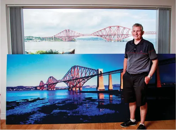  ??  ?? Double vision: Stuart Slicer with the huge photo of the Forth Bridge … in front of his window with its stunning view of the same bridge