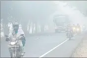  ??  ?? Commuters ride along the Bhadson road amid dense fog in Patiala in Punjab on Monday