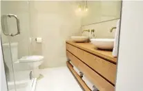  ??  ?? A solid cherry wood was used for the vanity and shelf in this master bath, and the two sinks are concrete painted white. These elements, along with the light coloured tiles, provided the rustic, natural vibe the homeowners were seeking.