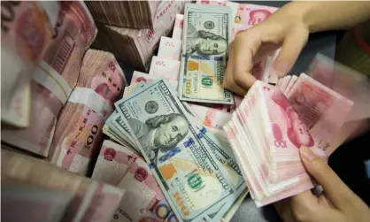  ??  ?? A Chinese bank employee counts yuan notes and dollar bills. China’s debt-to-GDP ratio has risen to 255% since 2010. Photograph: AFP/ Getty Images