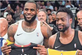  ??  ?? LeBron James and Dwyane Wade exchange jerseys after Monday’s game. They won two titles when they played for the Heat.