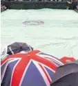  ?? Foto: dpa ?? Gewohntes Bild in Wimbledon: Zuschauer unter dem Schirm, Rasenplatz unter der Plane.
