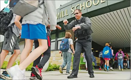  ?? SEAN D. ELLIOT/THE DAY ?? Stonington police Capt. Todd Olson offers double fist-bumps to students arriving Friday at Deans Mill School in Stonington as part of the High-Five Friday initative.