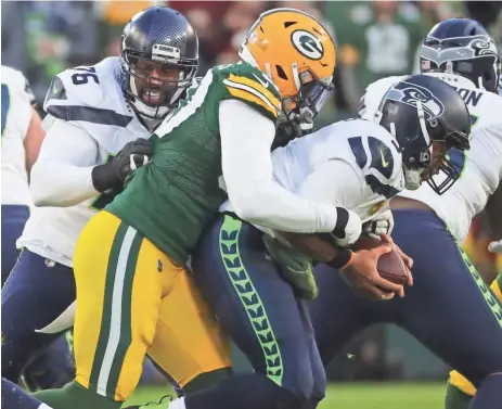  ?? MARK HOFFMAN / MILWAUKEE JOURNAL SENTINEL ?? Packers defensive end Whitney Mercilus sacks Seahawks quarterbac­k Russell Wilson during the first quarter Sunday. Mercilus’ season may be over after he suffered injured biceps in the game.