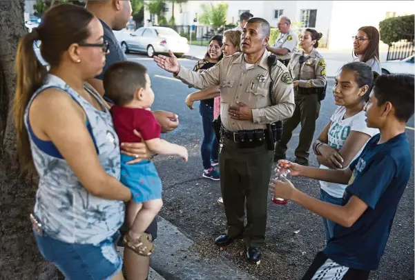  ??  ?? Sheriff’s deputy Marino Gonzalez (centre), talks with community members during a block meeting to assure them they can come forward to lodge reports of abuse without being questioned about their immigratio­n status.