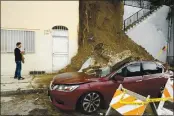  ?? DAMIAN DOVARGANES — THE ASSOCIATED PRESS ?? Michael Osborne, a film director, documents the damage after being able to open the door to his home, left, after a mudslide from beneath a house next to his home in Los Angeles on Jan. 18, 2019. No one was hurt.