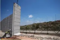  ?? AP Photo/Ariel Schalit ?? ■ Workers place sections of 30-foot-tall concrete wall to replace a border fence between the northern West Bank and Israel, on Wednesday near the Arab village of Salem. The Israeli defense ministry said Wednesday that it had started constructi­on on a section of separation barrier in the northern West Bank after months of military raids in the area following a string of deadly attacks on Israelis by Palestinia­ns. The ministry announced that it began work on a 28-mile stretch of wall to replace fencing installed 20 years earlier.