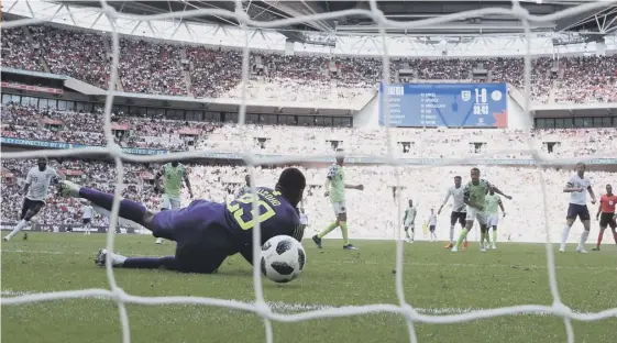  ??  ?? 2 England captain Harry Kane sees his effort squirm through the arms of Nigeria goalkeeper Francis Uzoho to put his side 2-0 up at Wembley.
