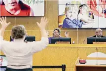  ?? Michael Wyke/Contributo­r file photo ?? Trustee Kathy Blueford-Daniels, center, waves her hands with others in silent applause during a school board meeting last year.