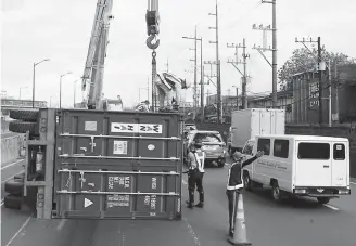  ??  ?? TRUCK ACCIDENT– Authoritie­s use a crane to lift a trailer truck that fell on its side along the North Luzon Expressway northbound near Camachile and Balintawak yesterday morning. The driver of the truck admitted that he fell asleep behind the wheel, causing the truck to veer and hit the median barrier of the highway. The accident caused a massive traffic jam along EDSA northbound, from Quezon City. (Mark Balmores)