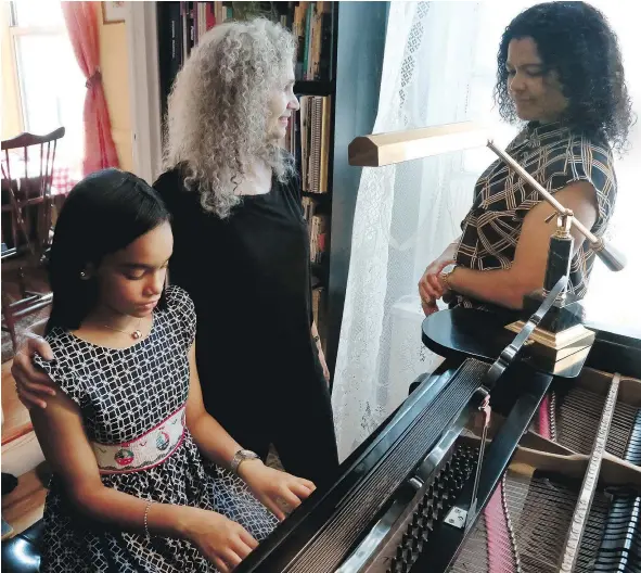  ?? — THE ASSOCIATED PRESS ?? Julie Wegener, centre, a music teacher with the MusicLink Foundation, her student Anmy Paulino Collado, left, and Anmy’s mom, Andolina Collado, wait as Anmy finishes a music session. Private lessons are beyond the reach of many families.