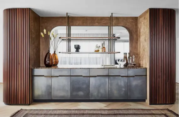  ??  ?? This page, from top Exuding opulence and a timeless elegance, the bar is the focal point of the entertaini­ng area. Tobacco-coloured stucco walls by White Acme. Emperador marble bar top by Granite & Marble Works with joinery by Made to Matter and JN Custom Metal. White vintage vase and Bellini tray, both from Becker Minty. Vessel on shelf from The DEA Store. Artifort ‘Mood Relax’ dining chairs from Ke-Zu surround the Bonaldo ‘Big Table’ from Fanuli. Christophe­r Boots ‘Oracle Triplet’ pendant light from Est Lighting hangs above. Sheer curtains by Simple Studio. Poltrona Frau leather bowl from Cult. Opposite page In the living area Flexform ‘Groundpiec­e’ modular sofa and ‘Sky’ coffee tables, all from Fanuli. Curtains by Simple Studio. Minotti Dibbets ‘Diagonal’ rug from De De Ce. Ceramic vase from Ondene. Velvet cushion and ceramic by Natalie Rosin, both from Jardan. Other cushions from Tigger Hall Design.