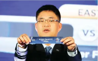  ??  ?? Shin Mangil, Asian Football Confederat­ion’s (AFC) director of the National Team Competitio­n holds the name card of Al-Ahli Football Club from Saudi Arabia in the draw for the 2017 AFC Champions League Knockout stage in Kuala Lumpur Tuesday. (AP)