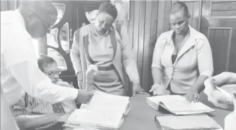  ??  ?? Chairman of the CoI into the operations of the City administra­tion retired Justice Cecil Kennard (second from left) along with legal assistant Sherwin Benjamin (left) examining the “missing record books” at City Hall while assistant Town Clerk Sherry Jerrick (right) looks on.