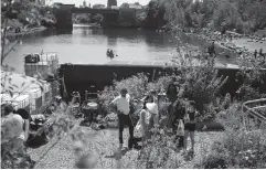  ?? Associated Press ?? n BELOW: A group of Kickstarte­r interns are lead through the Swale Garden on Wednesday in New York. The garden is an old constructi­on barge planted with vegetables, apple trees and fragrant herbs that gives New Yorkers a chance to pick their own dinners.