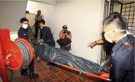  ??  ?? Gruesome find: Police officers carrying Cheah’s body out of the apartment in Taman Sri Sinar, Segambut.