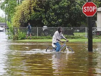  ?? Henrietta Wildsmith/ The Shreveport Times via AP ?? A man tries to bike through the flooding from the rains of storm Barry on Sunday on Louisiana Highway 675 in New Iberia, La. Barry dumped rain as it slowly swept inland through Gulf Coast states.