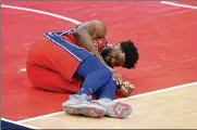  ?? NICK WASS/ASSOCIATED PRESS ?? Philadelph­ia 76ers center Joel Embiid grimaces after an injury Friday in Washington. Embiid has a bone bruise on his left knee and could miss at least two weeks.