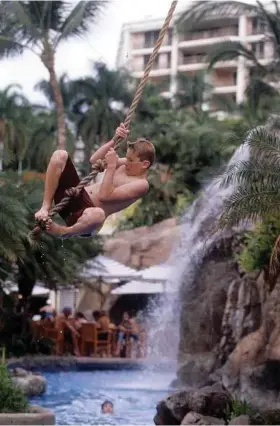  ?? Michael Goulding / Orange County Register ?? A young swimmer swings into the water at the Grand Wailea Resort on Maui. The resort is set within 40 lush, tropical acres.