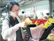  ?? SHI WENZHI / CHINA DAILY ?? A customer selects flowers at Kunming Dounan Flower Market in Yunnan province on Monday.