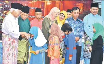  ??  ?? (Front, from left) Taib joins Talib, Zaliha, Rodziah, Dr Rundi and Dr Abdul Rahman in giving away ‘duit raya’ to orphans under Lakib’s care.