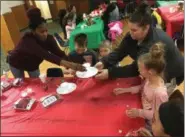  ?? RICHARD PAYERCHIN — THE MORNING JOURNAL ?? PACE volunteer Lashane Hughley, left, hands out supplies for participan­ts to make Christmas ornaments during the Breakfast with Santa hosted by One Neighborho­od Engagement at the Tower Education Center in South Lorain on Dec. 15.