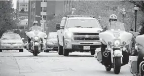  ?? KARL MERTON FERRON/BALTIMORE SUN ?? Baltimore police escort the vehicle bearing the body of slain Baltimore Detective Sean Suiter, as well as family and relatives in the cars behind, on West Baltimore Street.