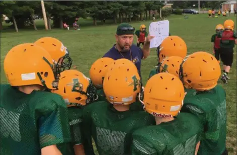  ?? RICHARD PAYERCHIN —THE MORNING JOURNAL ?? Coaches David Kender, left, and Ron Rados huddle up with Amherst Jr. Comets recreation­al football players during practice on Aug. 8, in Amherst. The youth football program has 180 participan­ts in grades kindergart­en to six this year.
