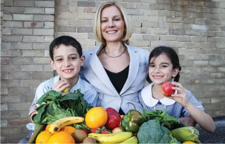  ??  ?? HELP AT HAND: Naturopath Carolyn Ledowsky, above with schoolchil­dren, says we can’t do anything about the genes we have but we can change the way they act.