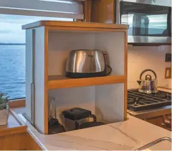  ??  ?? An electric lift is a creative stowage solution in the galley; the Polsters chose their galley appliances based on what they have at home; an optional electric partition separates the salon from the pilothouse and reduces light and distractio­ns when...