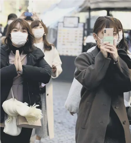  ?? PICTURE: AFP/GETTY ?? 0 Tourists wear protective face masks in Milan after the Covid-19 coronaviru­s spread to Italy