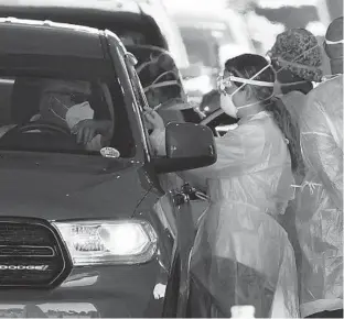  ?? JOE RAEDLE/GETTY IMAGES ?? Health care workers administer a COVID-19 vaccinatio­n to people at a drive-thru site at the Hard Rock Stadium on Jan. 6.