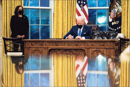 ?? Doug Mills / Pool / TNS ?? President Joe Biden signs several executive orders directing immigratio­n actions for his administra­tion as Vice President Kamala Harris looks on in the Oval Office at the White House in Washington on Feb. 2.